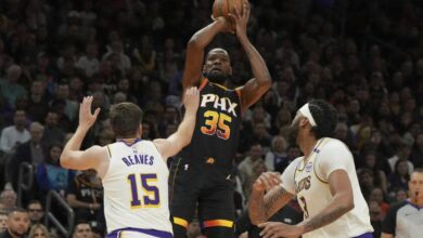 Suns forward Kevin Durant shoots over Lakers guard Austin Reaves and forward Anthony Davis Tuesday in Phoenix.